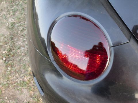 1999 Volkswagen Beetle - The taillight of a dark-colored vehicle is shown in detail, reflecting the surroundings.