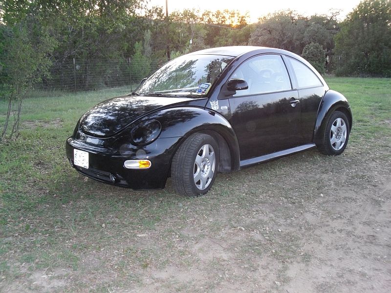 Black 1999 Volkswagen Beetle parked on a grassy area