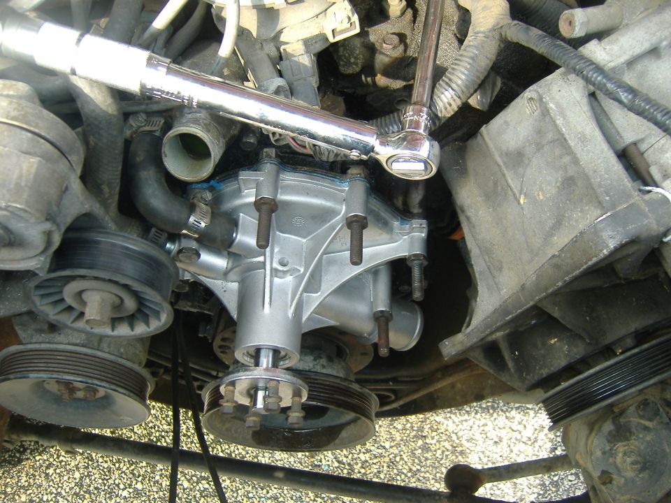 Engine bay view of front-mounted accessory component with breaker bar on bolts