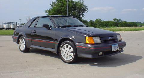 1976 Ford Ranchero - This dark coupe with a red stripe is parked outside on a sunny day. The vehicle's year is not identifiable.