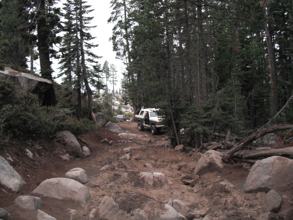White 1991 Ford Bronco on a rocky forest trail