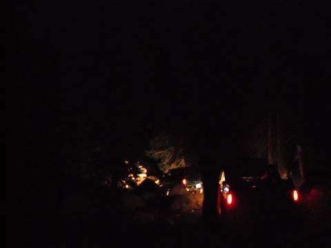 1991 Ford Bronco - Several SUVs navigate a dark, off-road path at night, illuminated by their headlights and taillights.