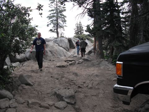 1991 Ford Bronco - A group of people hike up a , rocky trail with a black truck partially visible on the right side of the frame.