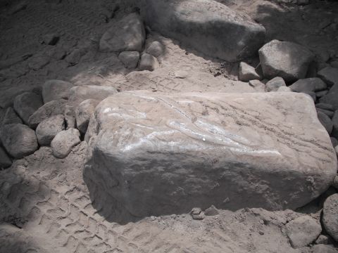 1991 Ford Bronco - A large rock with white markings sits on sandy ground, showing tire tracks from a vehicle.