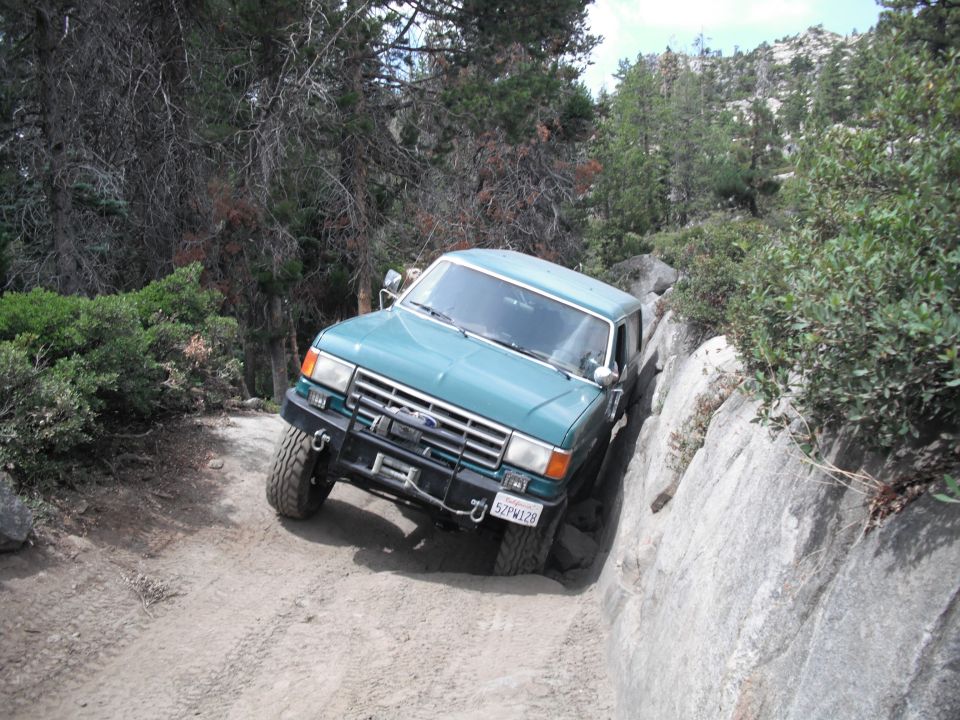 Green Ford F-Series truck navigating a rocky trail