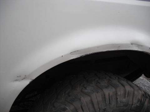 1991 Ford Bronco - Scratches and dirt are visible around the wheel well of this white vehicle.