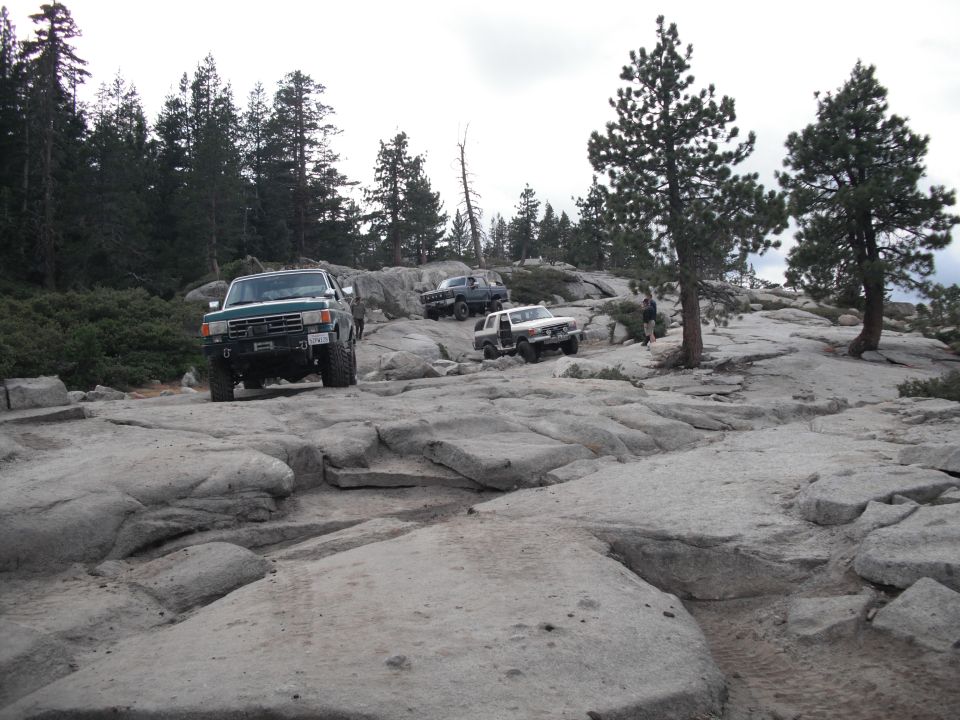 Green 1991 Ford Bronco driving on rocky terrain