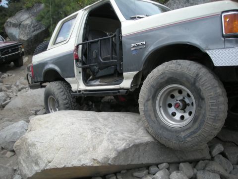 1991 Ford Bronco - A 1991 Ford Bronco navigates a rocky trail with its driver's door open.