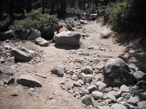 1991 Ford Bronco - Vehicles traverse a challenging rocky trail in a wooded area.