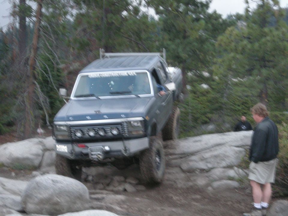 Gray Ford F-Series truck with aftermarket bumper and lights navigating rocky terrain