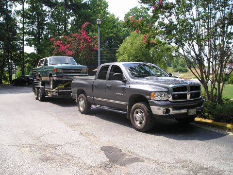 1989 Ford Bronco - A gray Dodge Ram pickup truck tows a green Ford Bronco on a trailer.