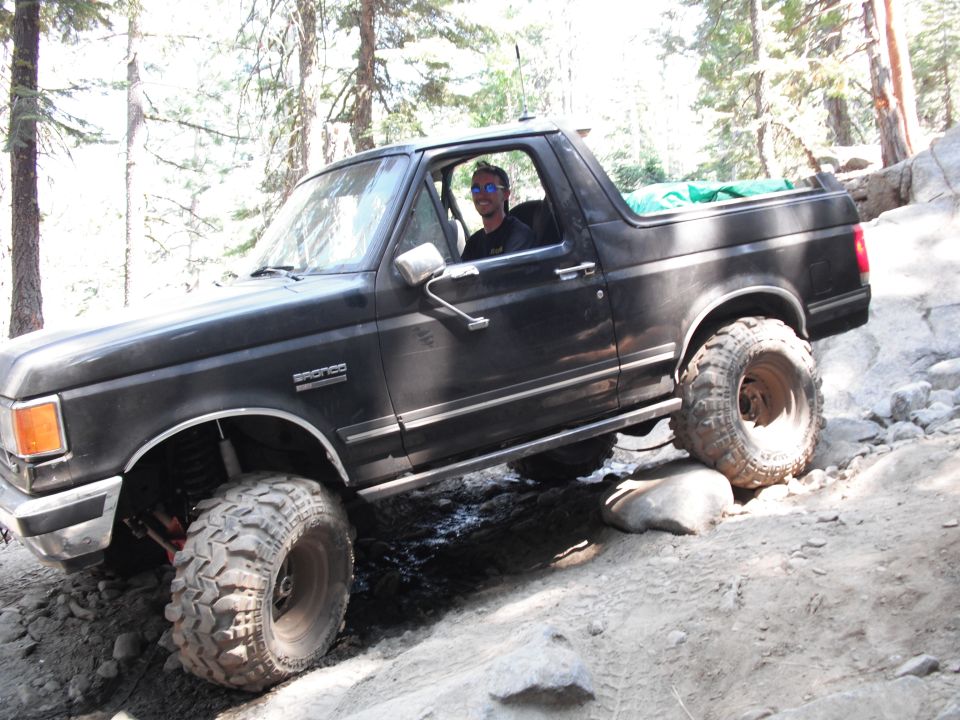 1991 Ford Bronco navigating rocky terrain with driver visible