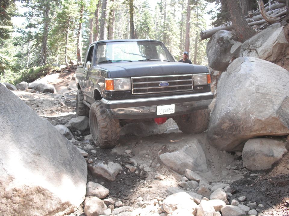 Black Ford F-Series truck navigating a rocky trail with large boulders