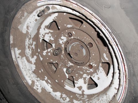 1991 Ford Bronco - This wheel and tire are covered in dried mud, suggesting off-road use.