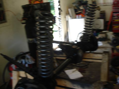 1978 Ford Bronco - Workshop scene with disassembled vehicle suspension components, including large coil springs and axles, on pallets.