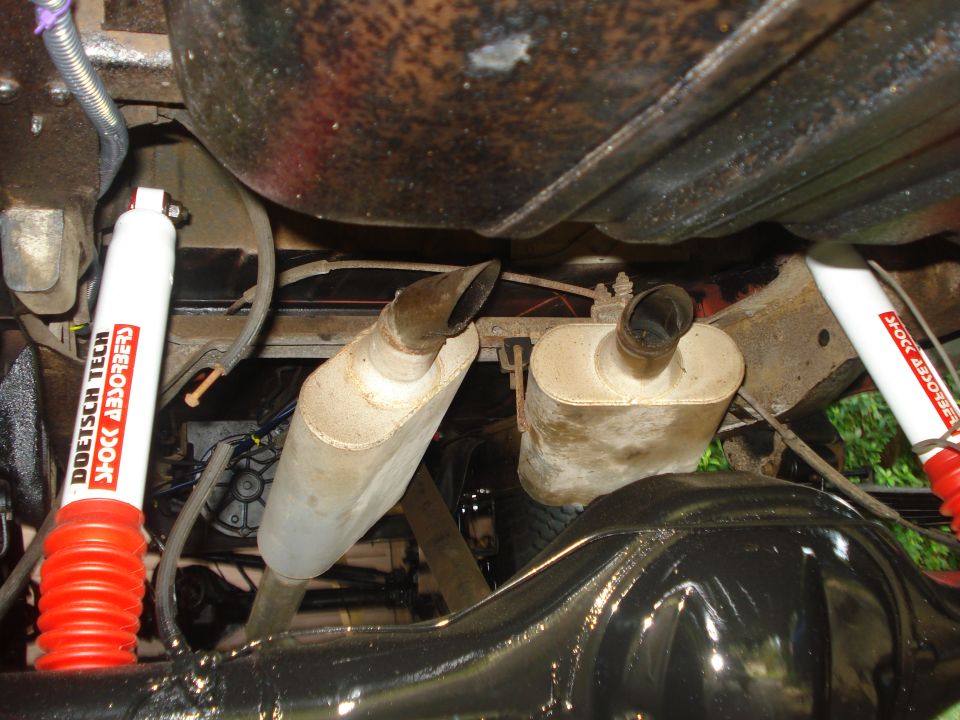 Underside of a vehicle showing dual mufflers, red and white Doetsch Tech shock absorbers, and a differential
