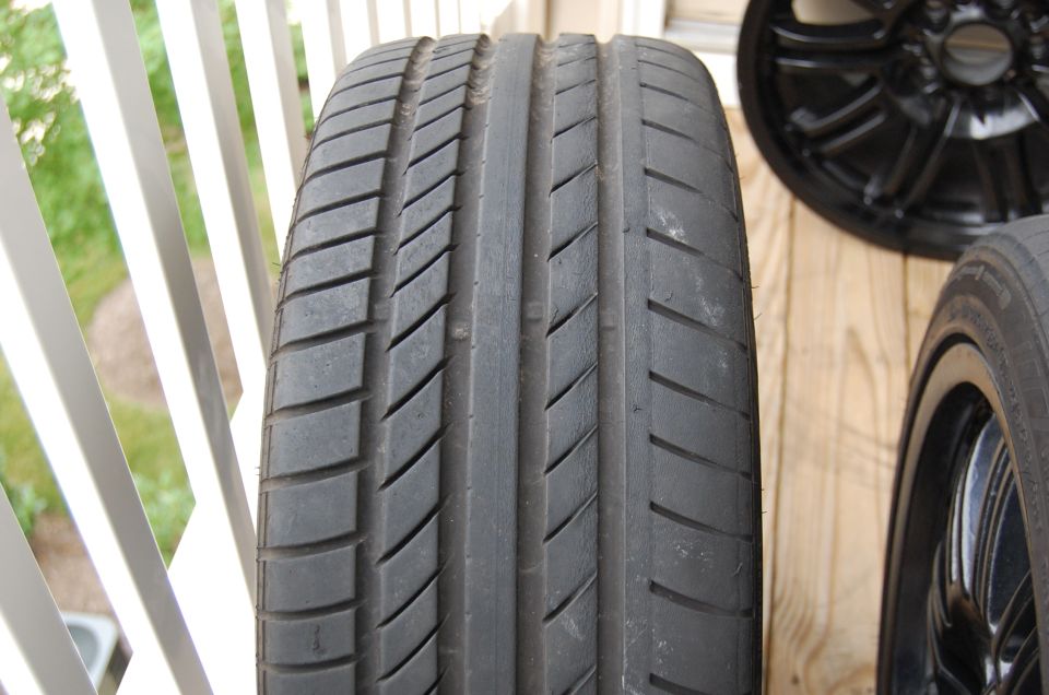 Close-up of used performance tire tread with black wheels behind on a deck