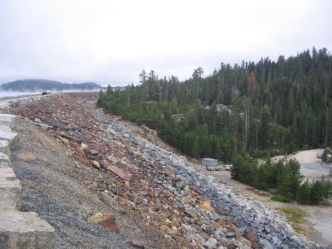 1989 Ford Bronco - A view of a dam's rocky slope and surrounding forest under a cloudy sky.