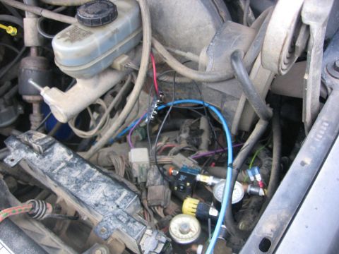 1989 Ford Bronco - Close-up view of a vehicle's engine bay, showing intricate wiring and air suspension modifications.