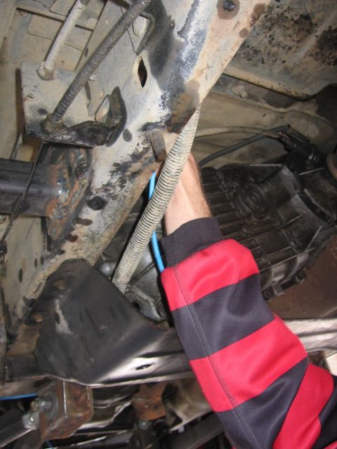 1989 Ford Bronco - Close-up view of the undercarriage of a vehicle, focusing on the frame and transmission components.