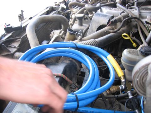 1989 Ford Bronco - A close-up view of an engine bay, a coiled blue hose and various engine components.