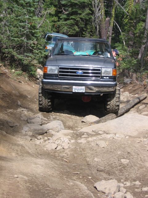 1989 Ford Bronco - Ford Bronco tackling an off-road trail, with a second vehicle visible in the background.