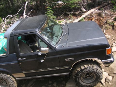 1989 Ford Bronco - This black Ford Bronco is navigating a rocky, wooded trail.
