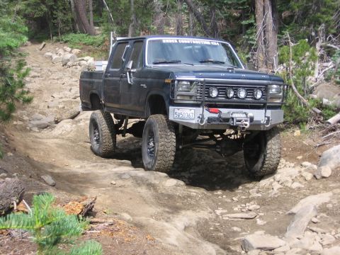 1989 Ford Bronco - Modified Ford pickup truck navigating a challenging off-road trail in the mountains.