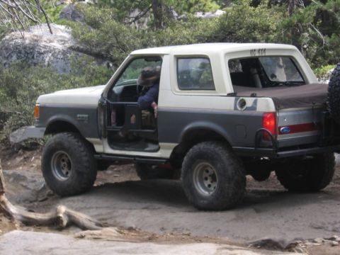 1989 Ford Bronco - This modified Ford Bronco is navigating a rough, off-road trail with its doors removed for better visibility and cooling.