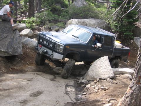 1989 Ford Bronco - Pickup truck navigating a difficult rocky off-road trail.