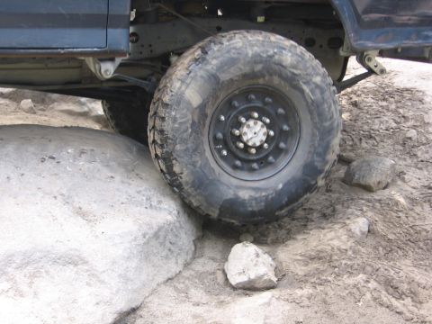 1989 Ford Bronco - The 1989 Ford Bronco navigates a rocky trail, with its large off-road tire positioned over a boulder.
