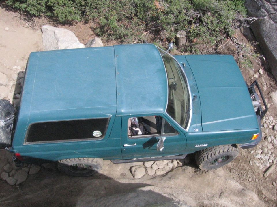 Teal SUV with off-road tires on a rocky trail, viewed from above