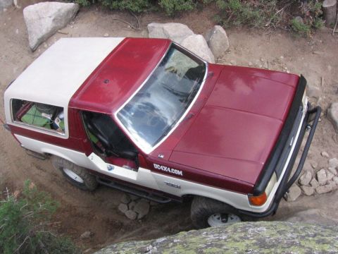 1989 Ford Bronco - This Ford Bronco is navigating a rocky trail, with its front right tire angled over a boulder.