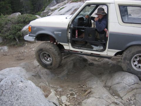 1989 Ford Bronco - A 1989 Ford Bronco navigates a rocky trail, its driver focused on the challenging terrain.