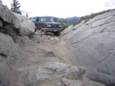 1989 Ford Bronco - A dark blue Ford F-Series truck navigates a challenging rocky terrain.