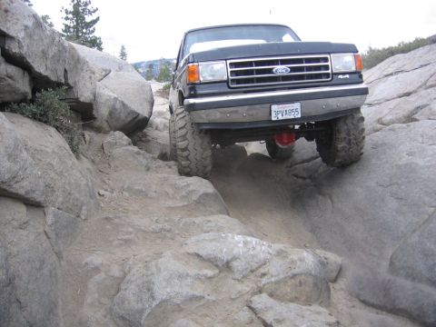 1989 Ford Bronco - Ford truck tackling a challenging off-road course with large rocks.