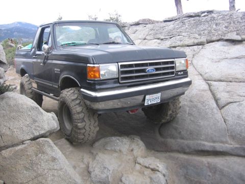 1989 Ford Bronco - This Ford Bronco is shown off-roading on a rocky trail, with its large tires gripping the uneven surface.