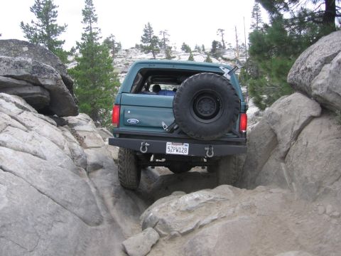 1989 Ford Bronco - A green 1989 Ford Bronco navigates a challenging rocky trail, its off-road capabilities.