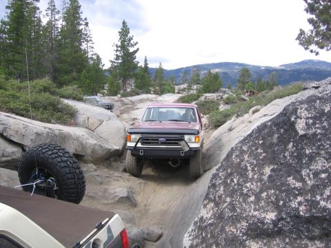 1989 Ford Bronco - A red 1987 Ford Bronco tackles a challenging rocky trail, with another vehicle visible in the foreground.