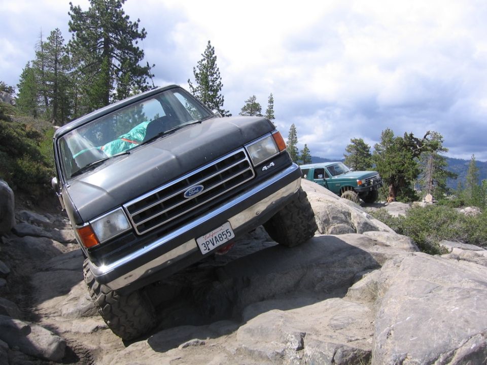 Dark gray Ford Bronco off-roading on rocks, front 3/4 view. License plate 3PVA855