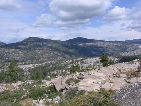 1989 Ford Bronco - A wide view of a rocky, forested mountain landscape under a partly cloudy sky.