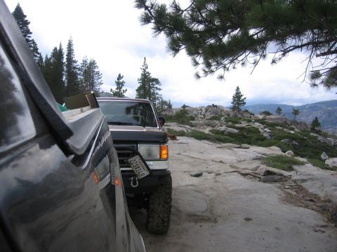 1989 Ford Bronco - A 1989 Ford Bronco is seen parked on a rocky landscape, with another vehicle partially visible in the foreground.