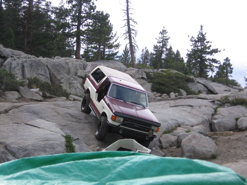 1989 Ford Bronco climbing over large rocks on a trail