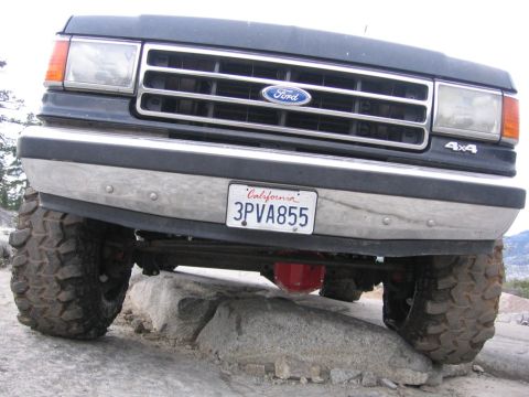 1989 Ford Bronco - This Ford Bronco is navigating rocky terrain, showing its front grille and off-road tires.