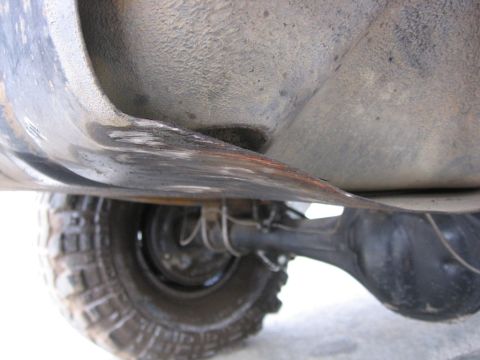 1989 Ford Bronco - Close-up of a vehicle's undercarriage, focusing on the rear axle and a damaged metal part.