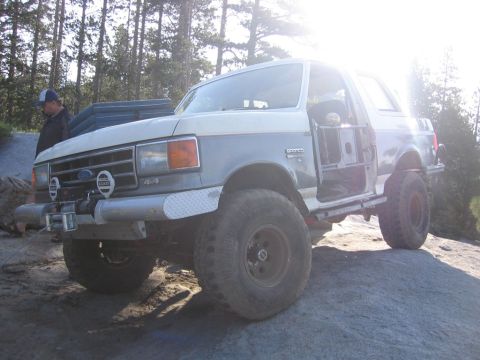 1989 Ford Bronco - This modified Ford Bronco is positioned on a rocky incline, with its doors taken off for off-road use.