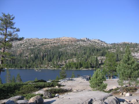 1989 Ford Bronco - A natural landscape a calm lake surrounded by dense evergreen forests and rocky terrain.