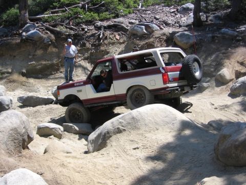 1989 Ford Bronco - This 1989 Ford Bronco is shown tackling a challenging off-road course with large rocks and sandy inclines.