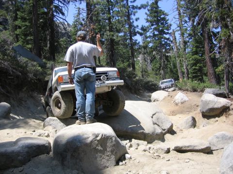 1989 Ford Bronco - A white SUV navigates a challenging rocky trail with another vehicle following behind.