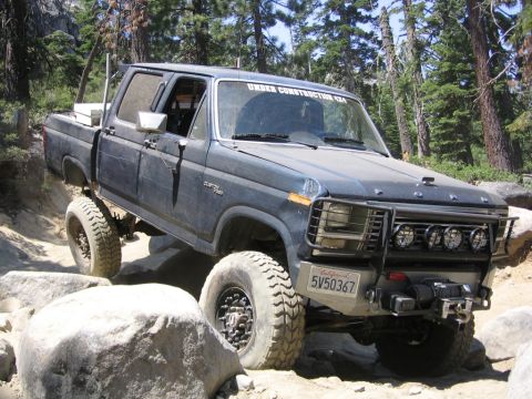 1989 Ford Bronco - Ford pickup truck with lifted suspension and off-road tires on a rocky trail.